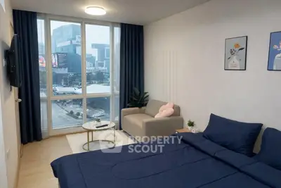Modern bedroom with city view, cozy sofa, and stylish decor in a high-rise apartment.