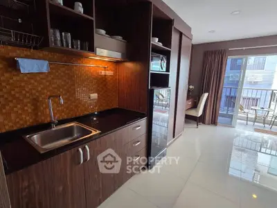 Modern kitchen with sleek cabinetry and open layout leading to a bright balcony view.