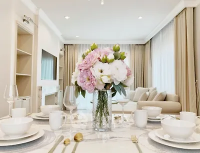 Elegant living room with stylish decor and dining setup, featuring a cozy sofa and large windows.