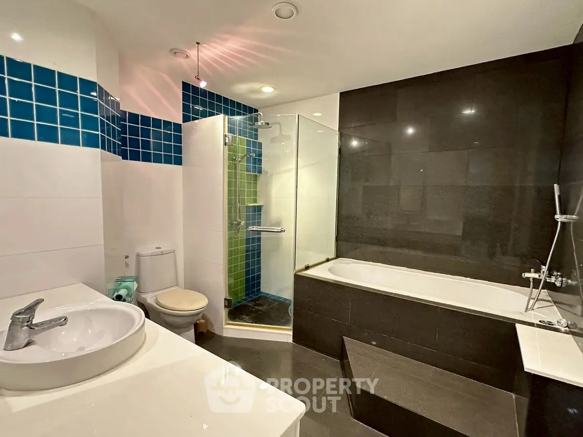 Modern bathroom with sleek design, featuring a bathtub and glass-enclosed shower.