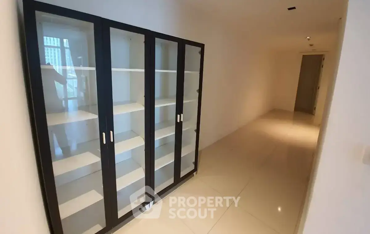 Spacious hallway with sleek glass cabinet and polished tile flooring in modern apartment.