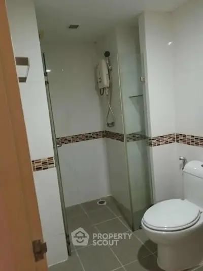 Modern bathroom with glass shower and white tiles in a real estate property.