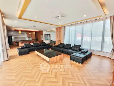 Luxurious open-layout living room with modern black sofas and elegant wooden flooring.