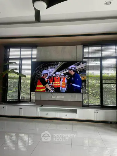 Spacious modern living room with large windows and sleek entertainment setup.