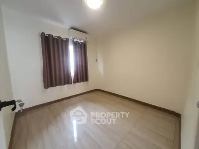 Spacious empty bedroom with tiled flooring and air conditioning, ready for customization.
