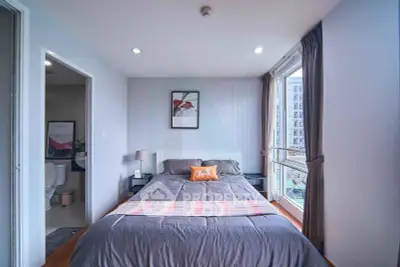 Modern bedroom with large window and city view, featuring stylish decor and cozy ambiance.