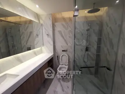 Luxurious modern bathroom with marble tiles and glass shower enclosure