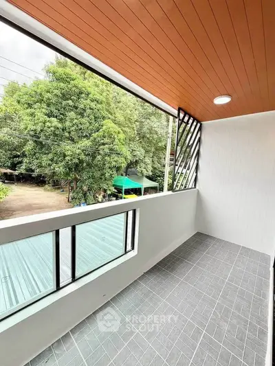 Spacious balcony with modern design and scenic view of lush greenery.