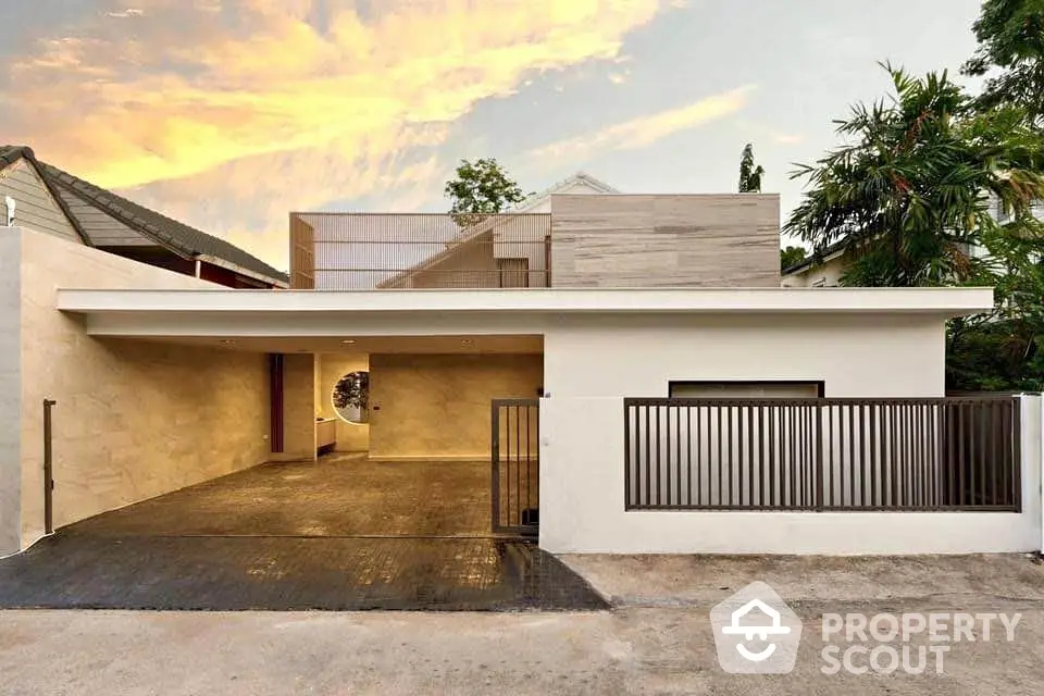 Modern minimalist house exterior with spacious driveway and elegant facade at sunset.