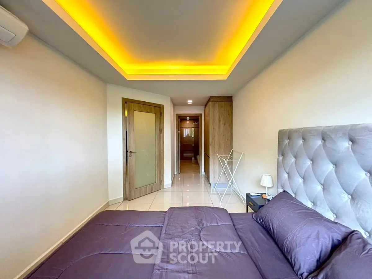Modern bedroom with stylish lighting and plush bedding in a contemporary apartment.