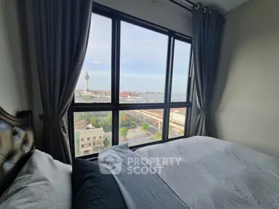 Stunning bedroom with large window offering panoramic city and water views, perfect for relaxation.