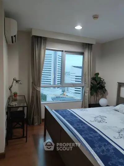 Cozy bedroom with city view, featuring a stylish bed, desk, and large window for natural light.