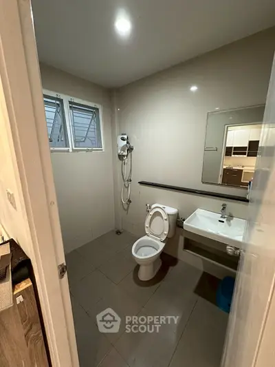 Modern bathroom with sleek fixtures and neutral tones, featuring a shower and toilet.