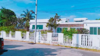 Charming single-story home with lush garden and white picket fence in sunny neighborhood.