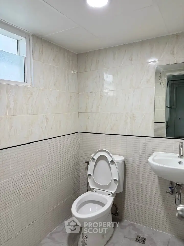 Modern bathroom with sleek tiles and compact fixtures, perfect for urban living.