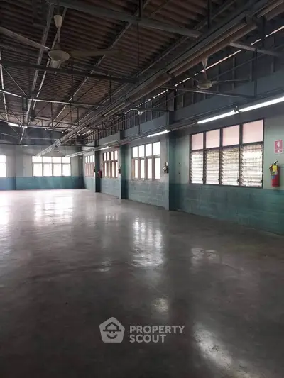 Spacious industrial-style interior with high ceilings and large windows, perfect for versatile use.