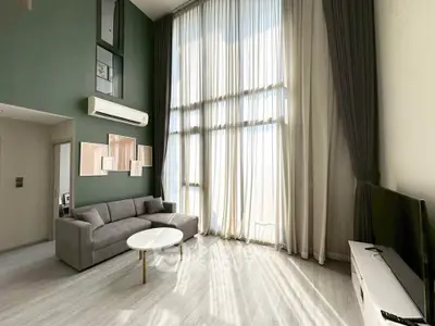 Spacious modern living room with high ceilings and large windows, featuring elegant decor and abundant natural light.