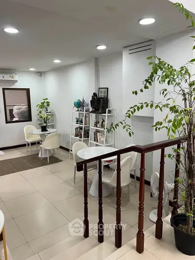 Modern living room with elegant decor and indoor plants, featuring white furniture and open layout.