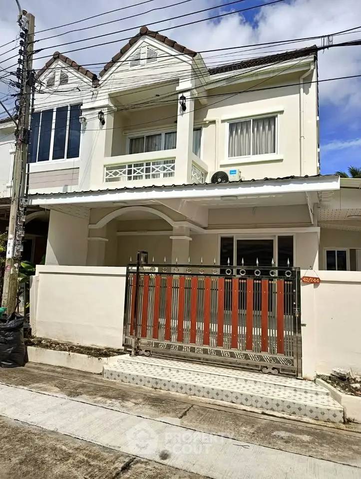 Charming two-story house with gated entrance and classic architectural design in a serene neighborhood.