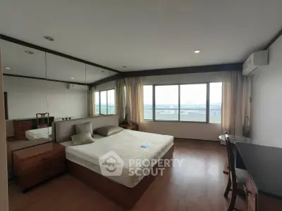 Spacious bedroom with large windows offering stunning city views, featuring modern furnishings and elegant decor.