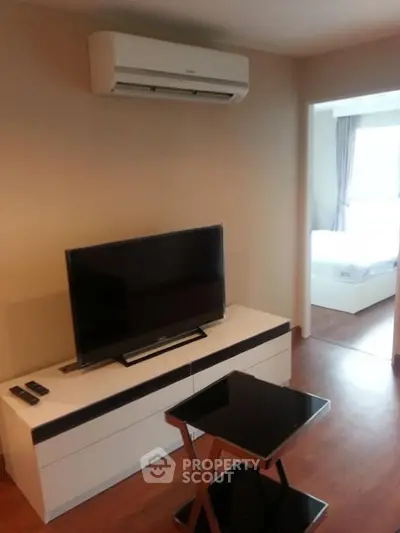 Modern living room with sleek TV setup and air conditioning, leading to a bright bedroom.