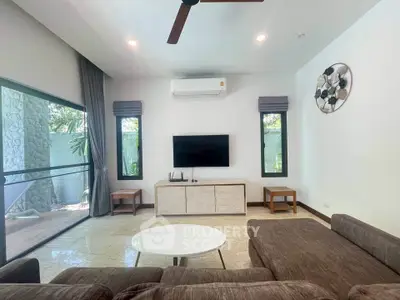 Modern living room with large windows, stylish furniture, and outdoor view, perfect for relaxation.