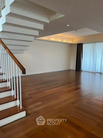 Spacious modern living room with elegant wooden flooring and stylish staircase