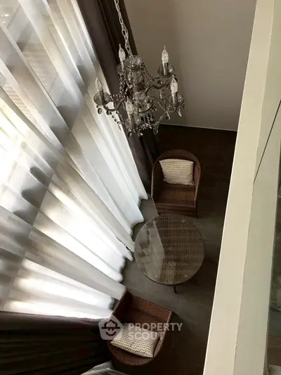 Elegant high-ceiling living room with chandelier and cozy seating area.