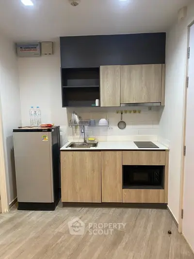 Modern compact kitchen with sleek cabinetry and appliances in a stylish apartment.