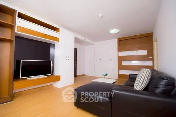 Spacious modern living room with sleek black sofa and built-in TV unit.
