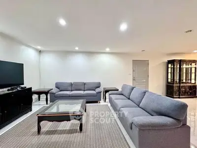 Spacious living room with modern gray sofas and elegant glass coffee table.