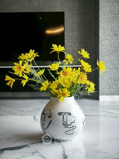 Elegant modern living room with stylish vase and vibrant yellow flowers on marble floor.