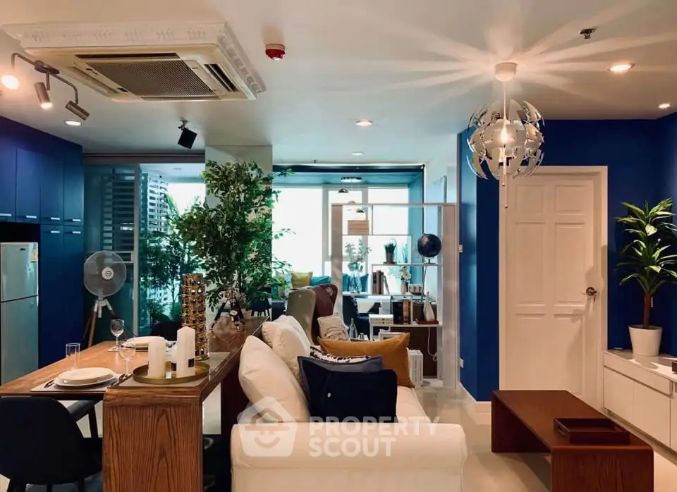 Stylish modern living room with blue accents and open layout, featuring cozy seating and elegant decor.