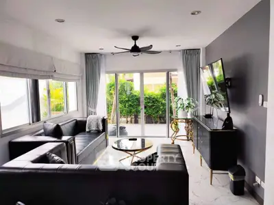 Modern living room with sleek black furniture and large windows for natural light.