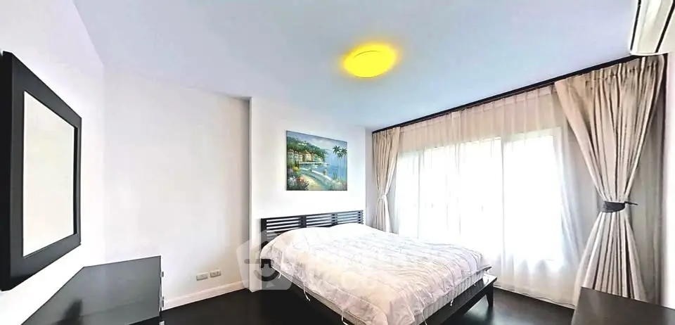 Spacious bedroom with modern decor and large window for natural light
