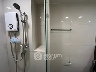 Modern bathroom with sleek shower and water heater, featuring clean white tiles and chrome fixtures.