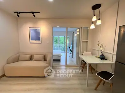 Modern open-plan living room with cozy seating and dining area, leading to a bright bedroom with balcony view.