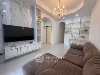 Elegant living room with chandelier, marble accents, and cozy brown sofa