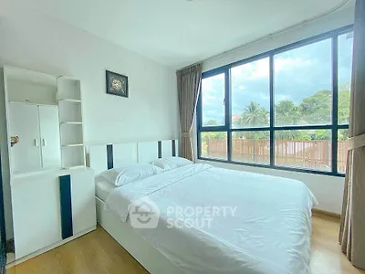 Bright and airy bedroom with large windows and modern furnishings, offering a serene view of lush greenery.