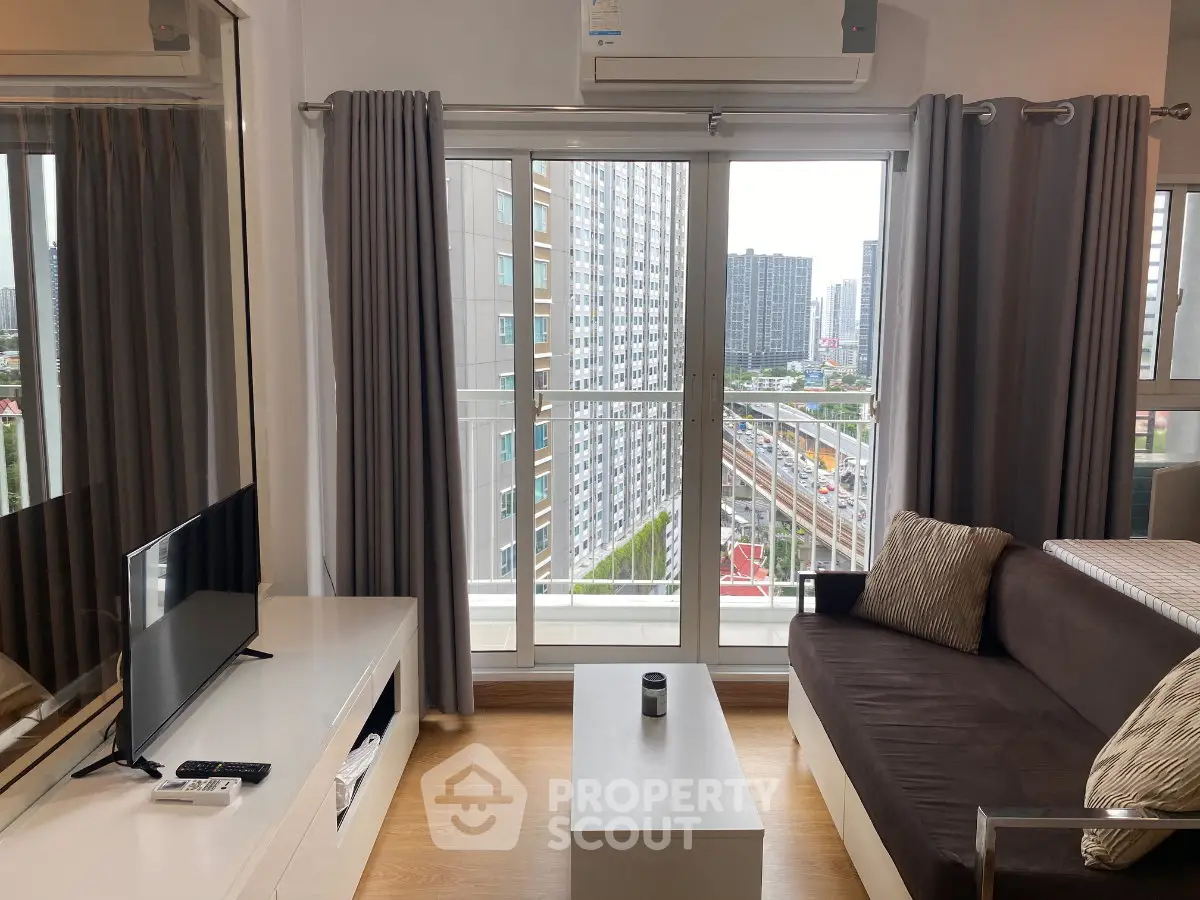 Modern living room with balcony view in high-rise apartment, featuring sleek furniture and large windows.