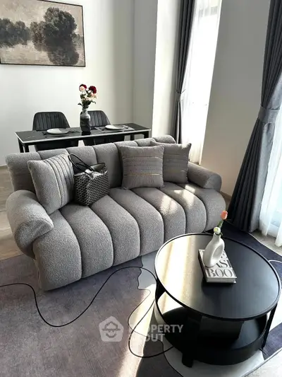 Stylish modern living room with plush sofa, elegant dining area, and chic decor in natural light.