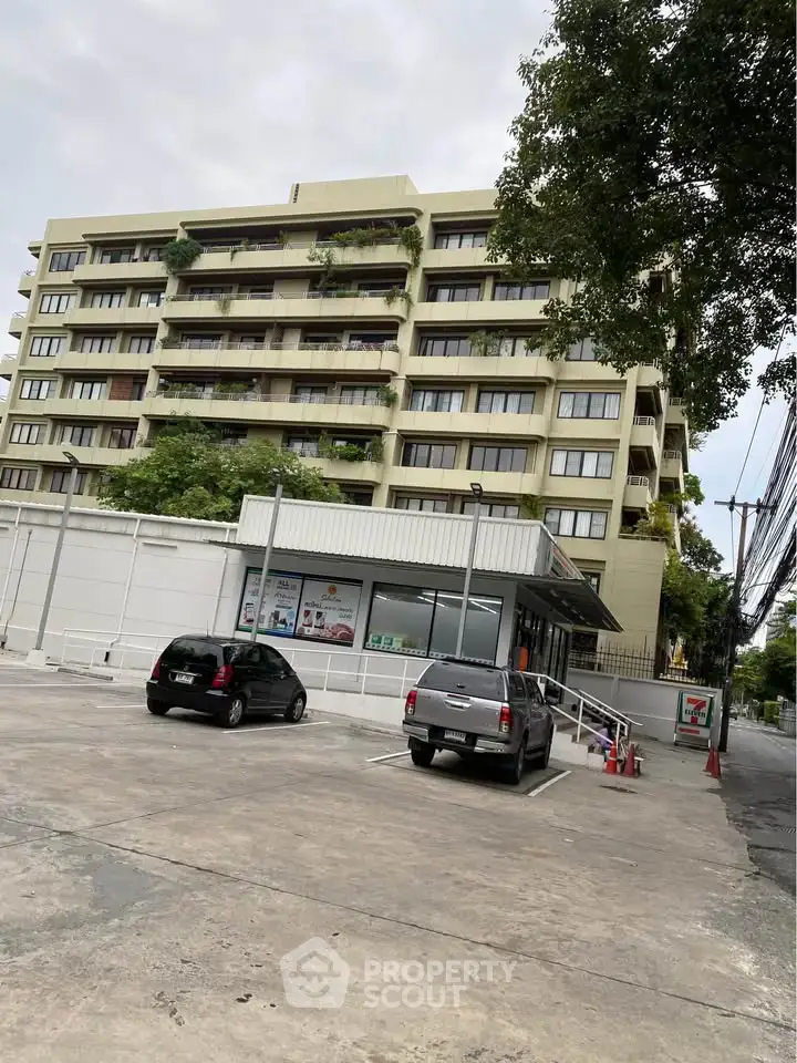 Modern multi-story building with parking area and lush greenery, ideal for urban living.