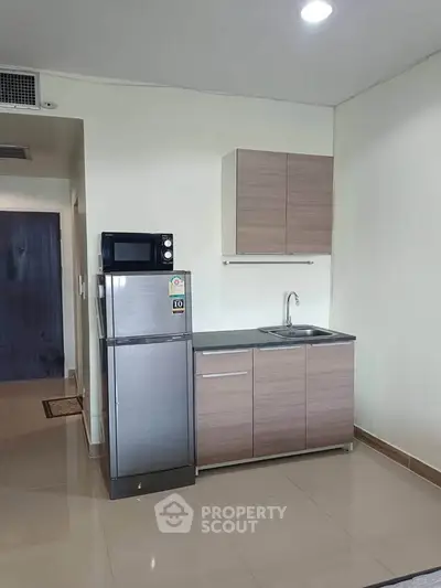 Modern compact kitchen with sleek cabinets and stainless steel appliances in a stylish apartment.
