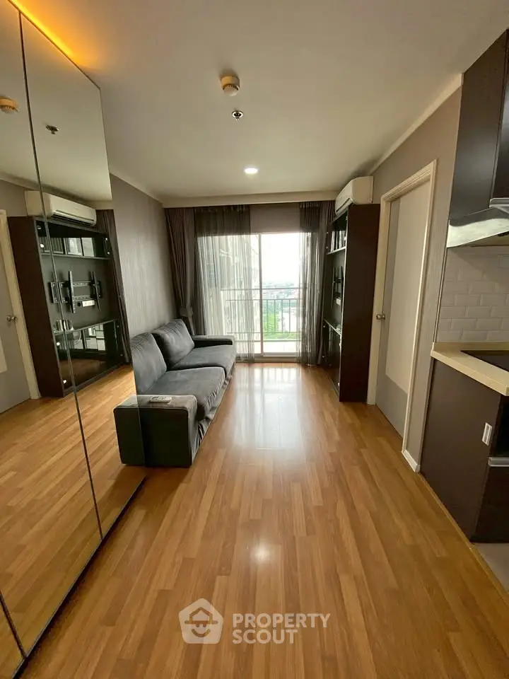 Modern living room with wooden flooring, large mirror, and balcony view.