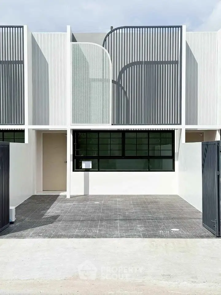 Modern minimalist townhouse exterior with sleek design and gated entrance.
