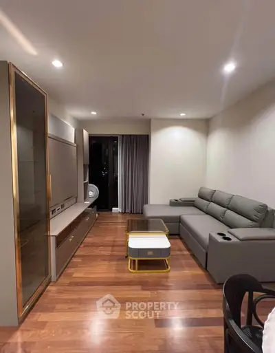 Modern living room with sleek furniture and wooden flooring, featuring a cozy sectional sofa and stylish decor.