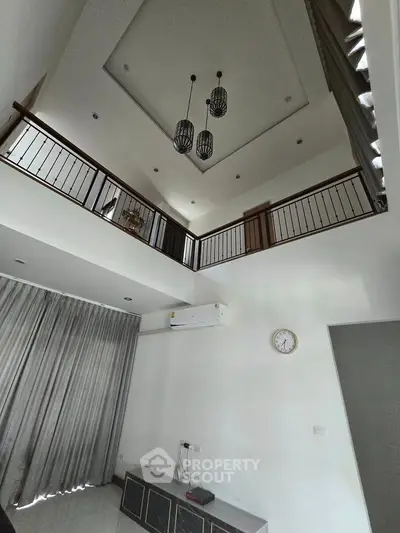 Spacious modern living room with high ceiling and elegant lighting fixtures.