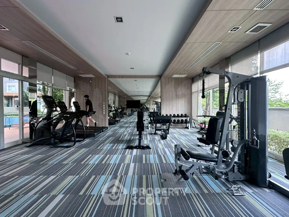 Spacious modern gym with state-of-the-art equipment and large windows offering natural light.