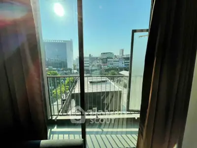 Bright city view from a modern apartment balcony with glass doors and urban skyline.