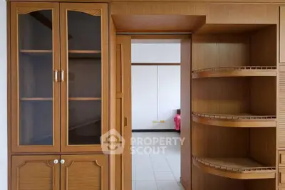 Spacious wooden storage unit with open shelves and glass cabinets in a modern interior.